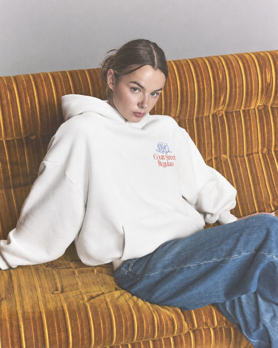 Court Street Regulars White Hoodie — model couch shot